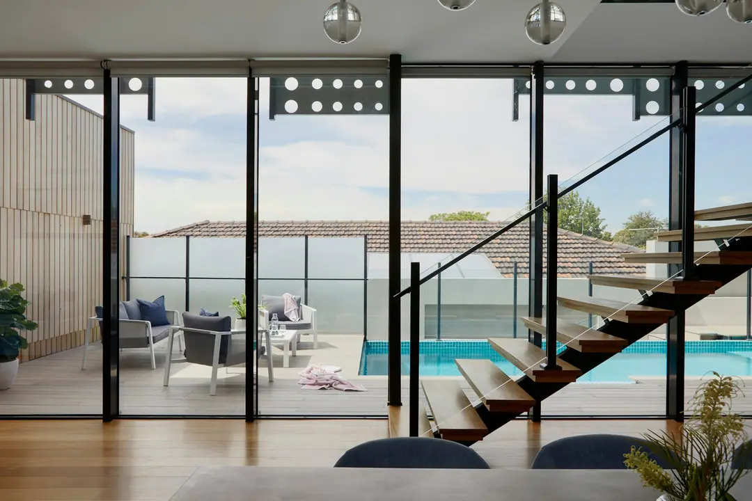 Escalier suspendu derrière une baie vitrée ouvrant sur la piscine