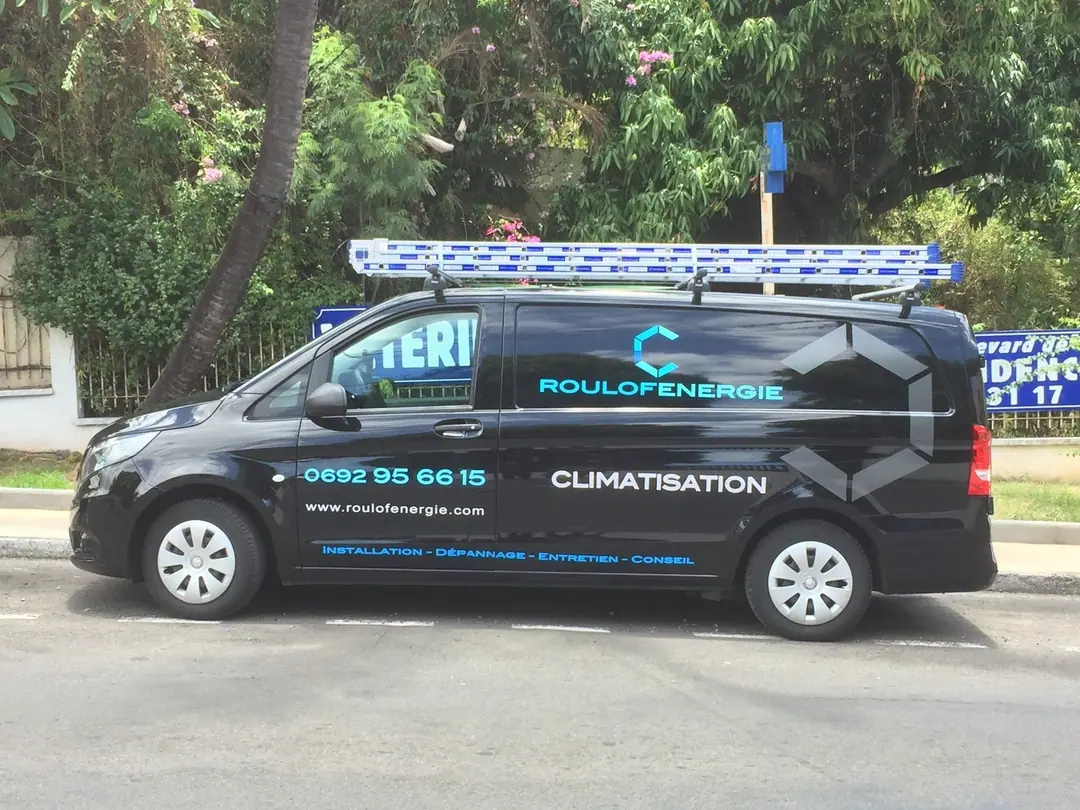 Le fourgon noir Roulof Énergie, lettrage bleu glacier, garé sous les arbres à La Réunion